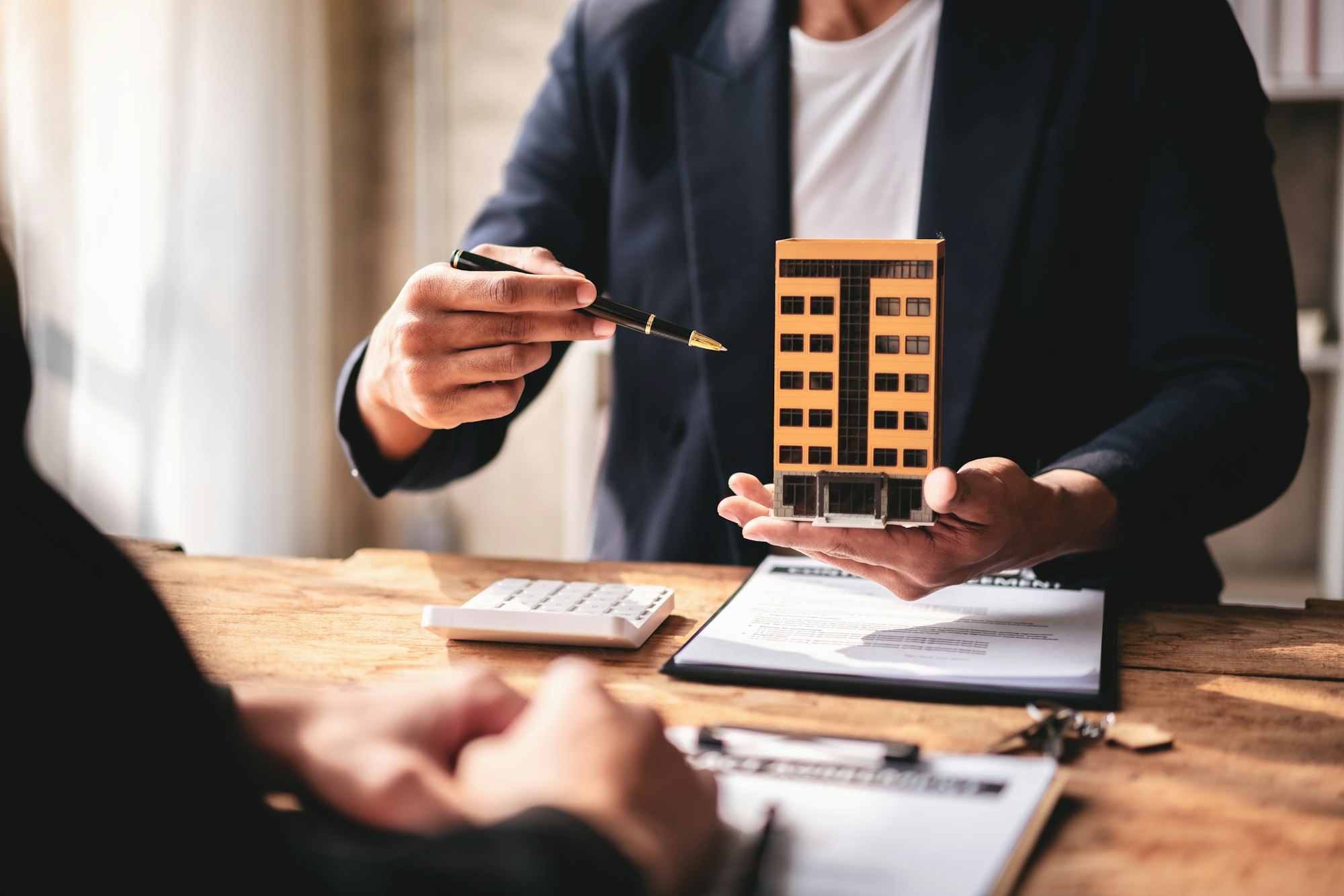 A man is holding a model of a building and pointing to it